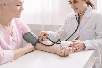 Doctor measuring arterial blood pressure for senior patient